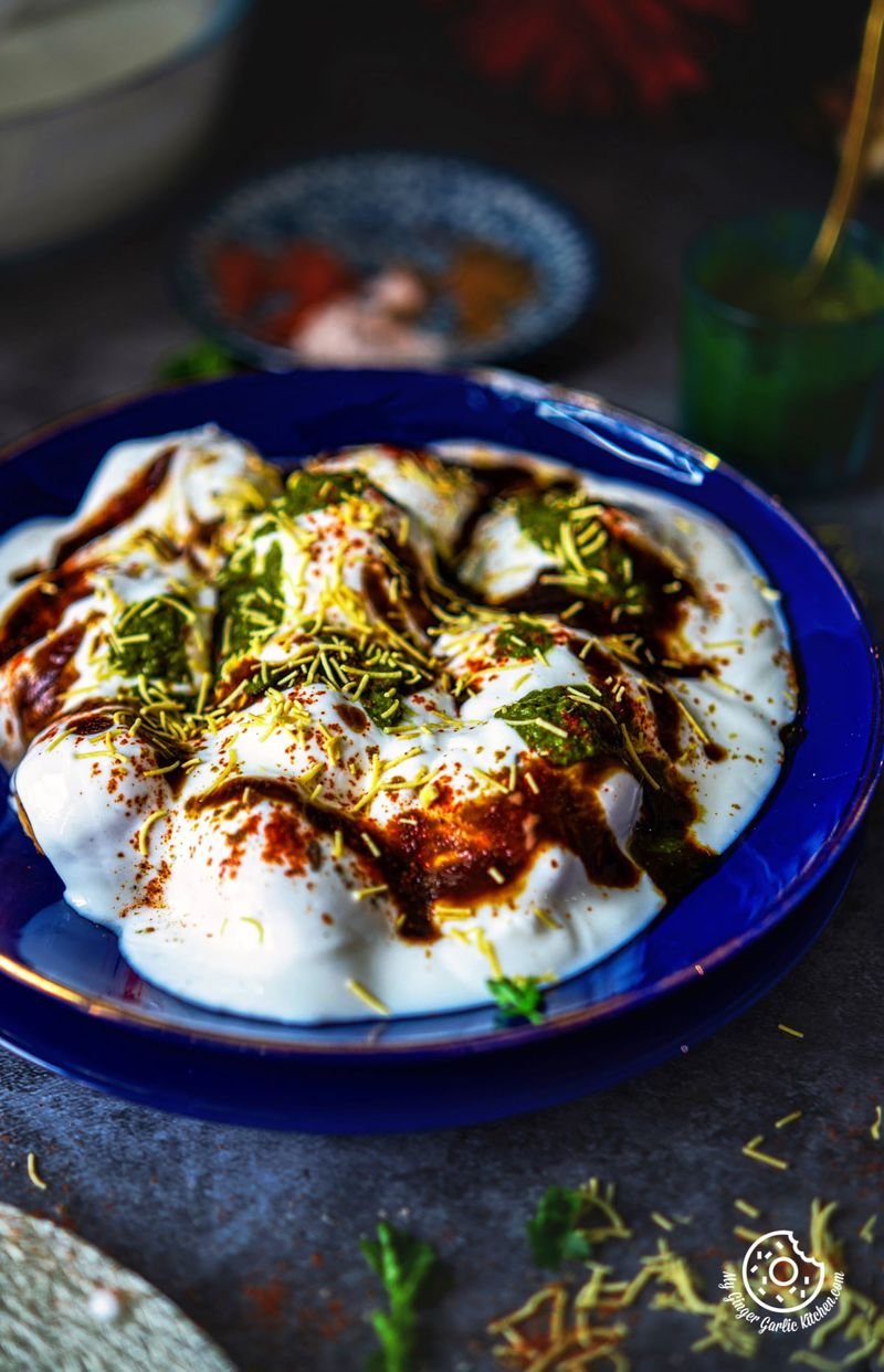 Dahi bhalle served in a bowl with pomegranate seeds.